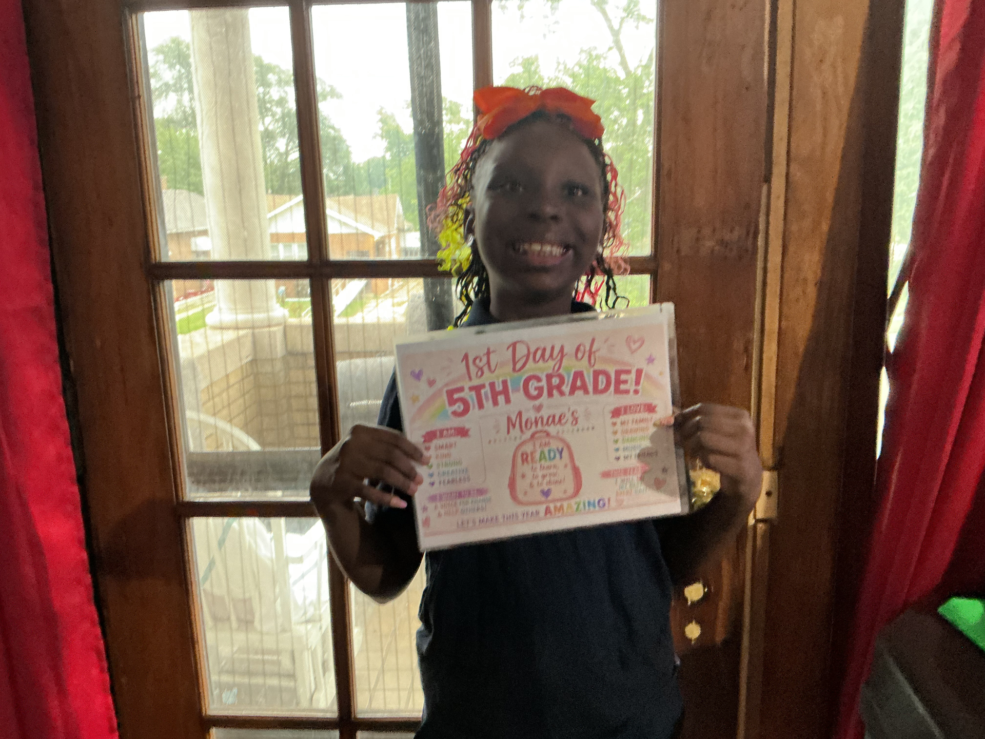 Monae smiling, holding her first day of school sign