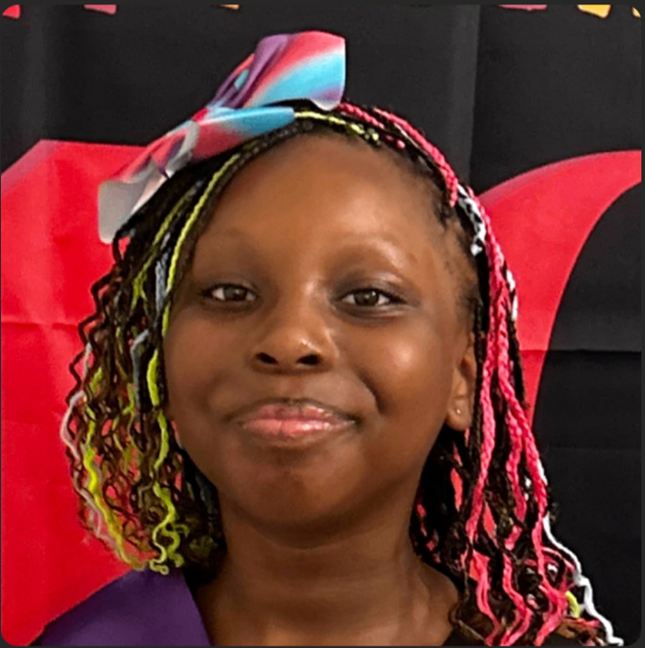 Monae smiling, holding her first day of school sign